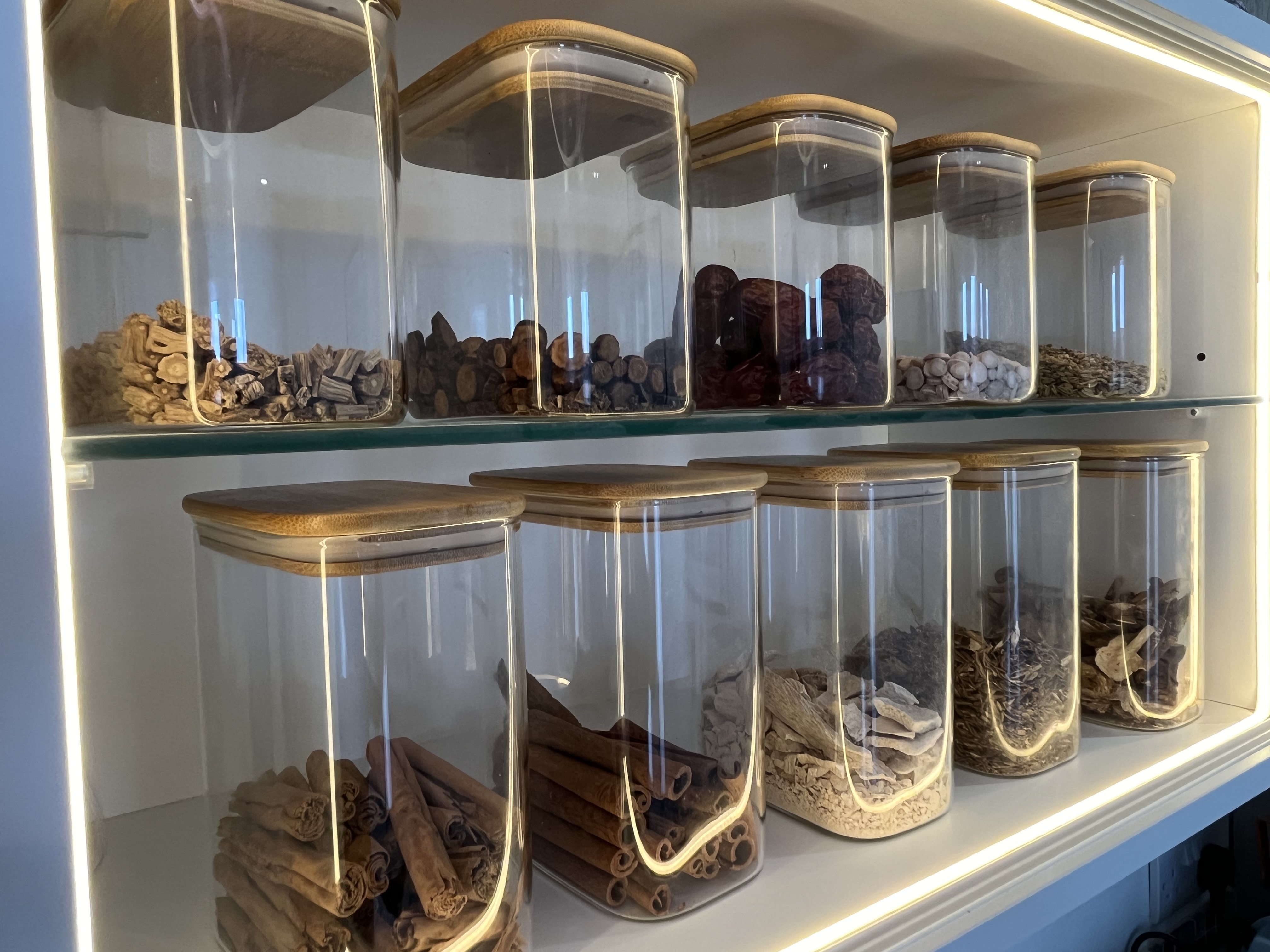 Close-up of glass herb jars on backlit shelves at Balance Acupuncture