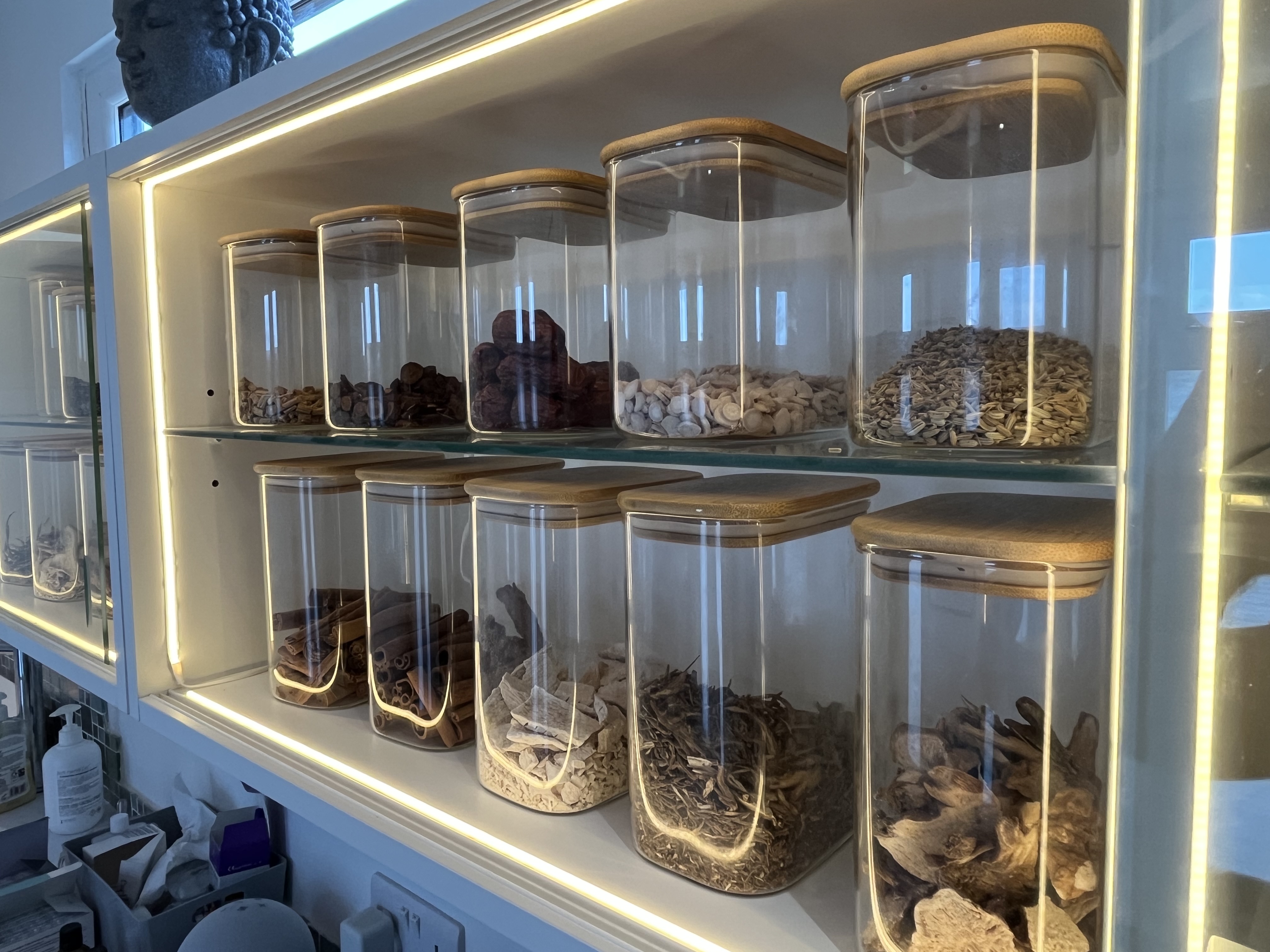 Chinese herbal medicine jars at Balance Acupuncture, warm backlit shelves