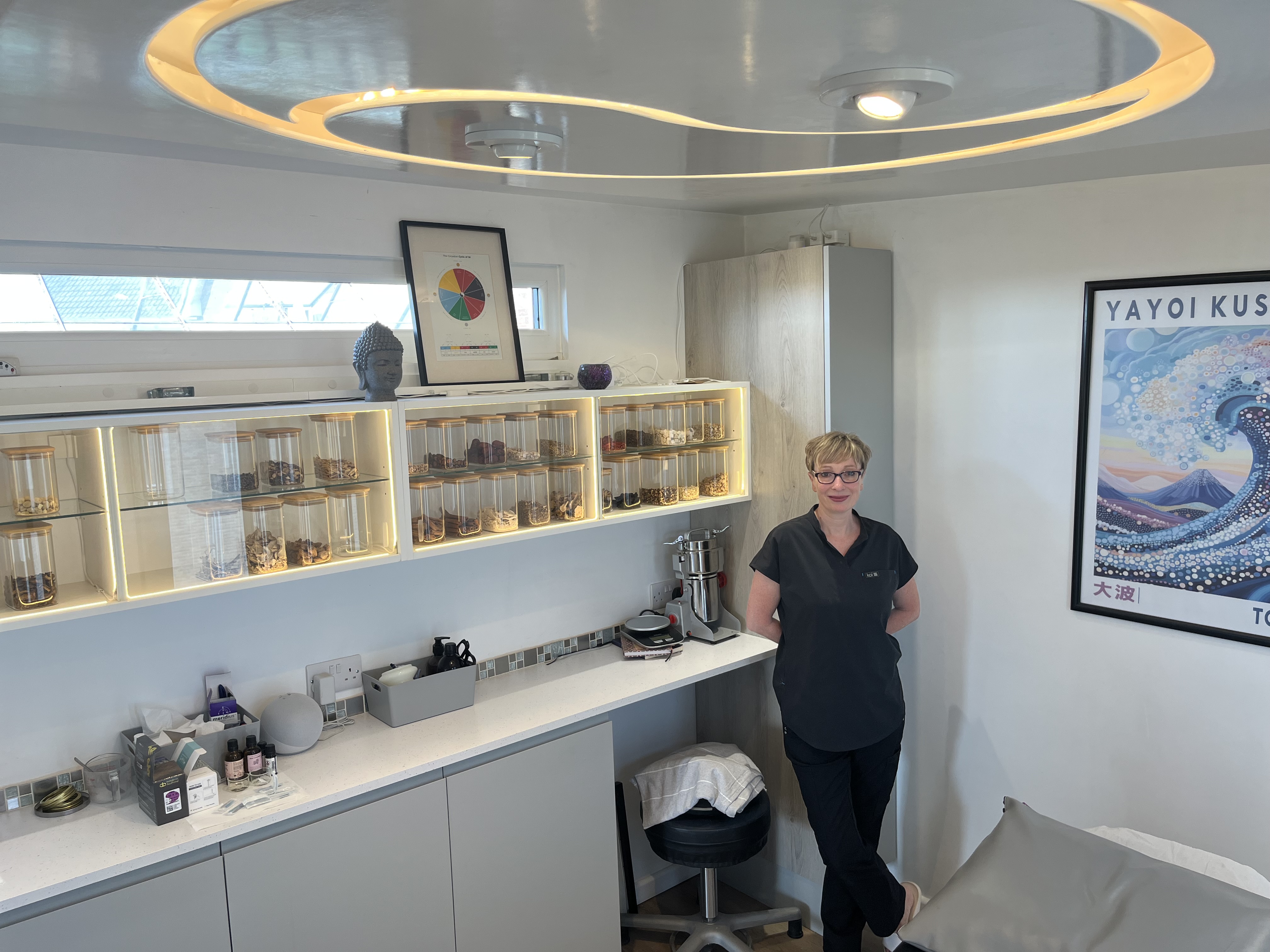 Sue, practitioner at Balance Acupuncture, standing by a sunny window overlooking fields